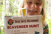 Robinia Tucker Simone holds up her completed reading scavenger hunt form, earning her a badge