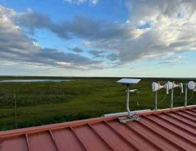 A Starlink unit is seen mounted alongside other networking equipment on top of the Alakanuk School