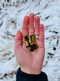 open palm holds gun shell casings against snowy background