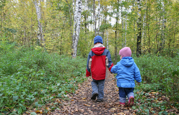 Young kids walking through the woods, bundled against the cold.