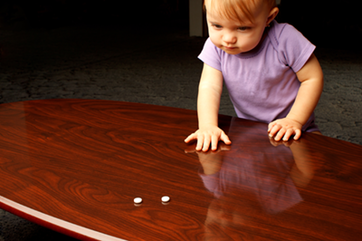 Baby reaching for pills that were left on the table.
