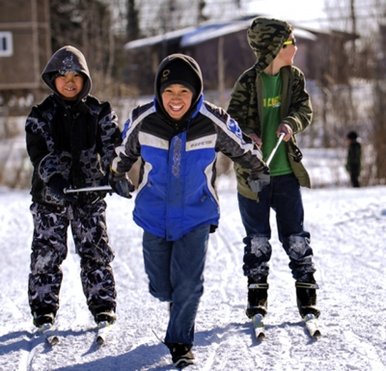 A child towing two friends on skis using their ski poles