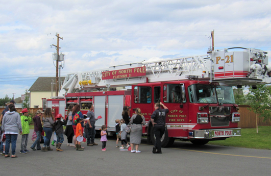 Children and families line up to climb into a fire truck at the monthly North Pole immunization clinic. 