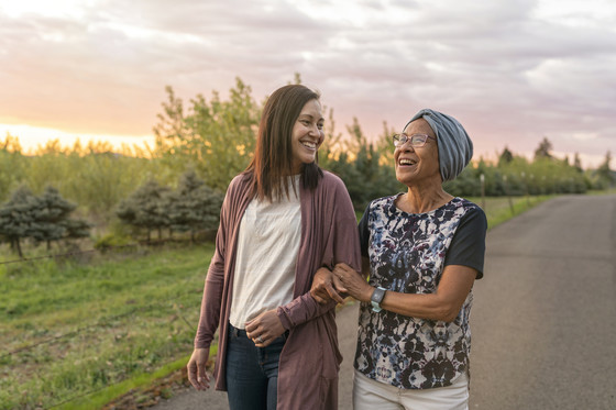 An older woman and a younger woman go for a walk together at sunset.
