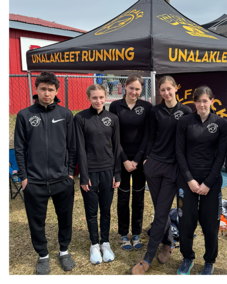 Unalakleet Running Club athletes smiling as a team in front of their new tent provided by the Game Changer Program