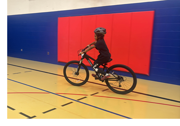 Jeriah rides his new bike, bike gloves, and helmet - all, plus a bike lock, were provided by the Game Changer program