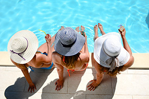 Women by pool with hats