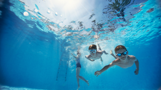 Three young children wearing googles swimming underwater