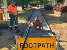 Men in hi visability clothes construct a footpath in front of a footpath closed sign