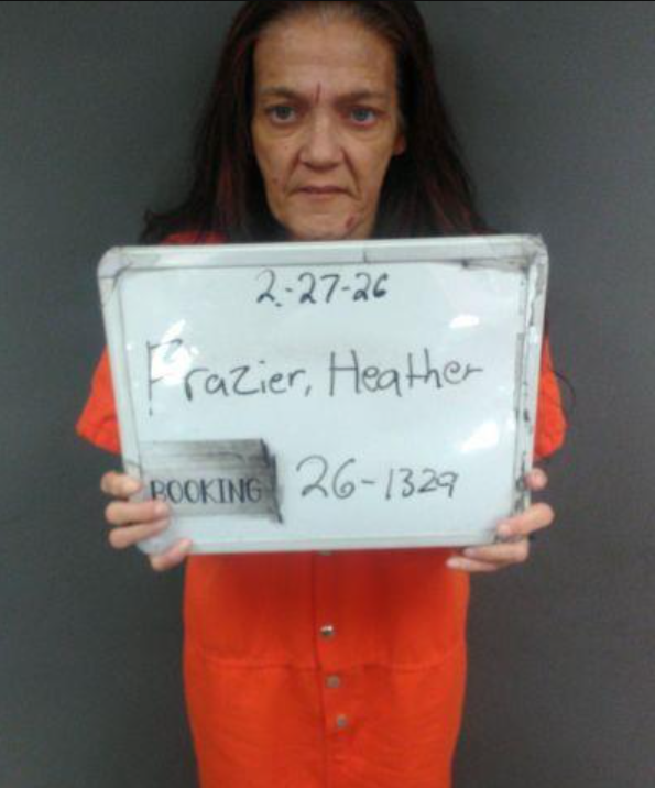 Heather Frazier, 45, a woman with brown hair, light skin, and in orange jumpsuit holding a booking sign