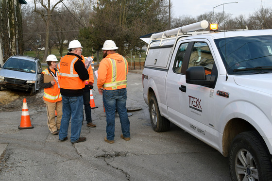Uniformed workers conversing near a TREKK marked vehicle