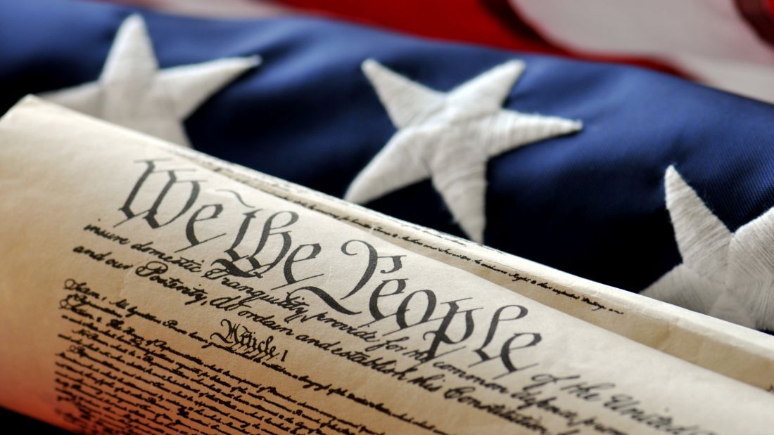 American Flag displayed with rolled copy of Constitution