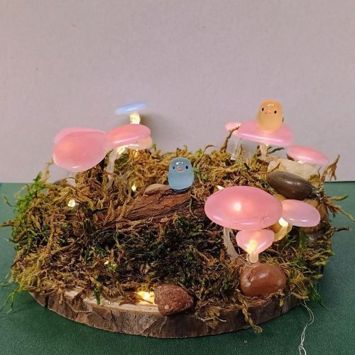 A miniature garden with mushrooms, moss and resin birds.