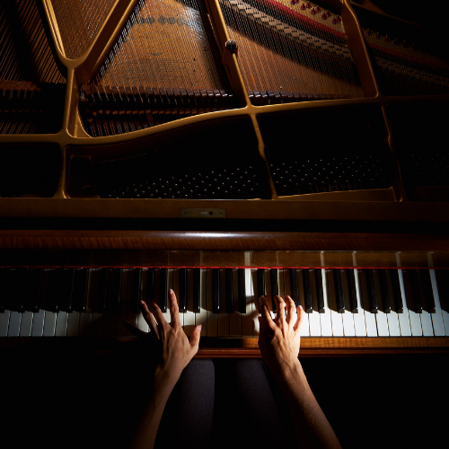 A Closeup of a persons hands playing a grand piano