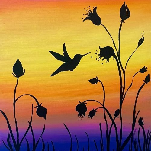 A silhouette of a hummingbird hovers near dark flowers against a vibrant sunset sky with pink, orange, and yellow hues.