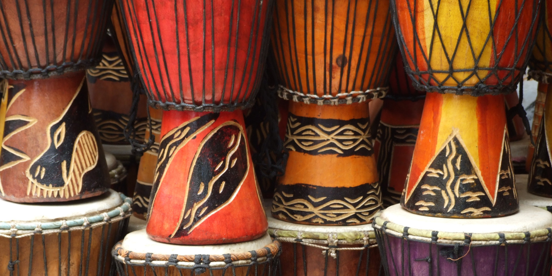 A collection of colorful, handcrafted drums with intricate patterns and designs.
