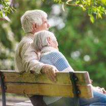 older retired couple sitting on a bench