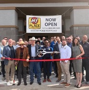 Councilmember, Mayor, and other officials holding large scissors for ribbon cutting in front of MyPlace Hotel in Mesa.