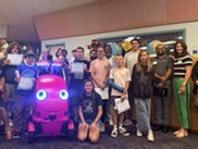 Group of students and adults holding certificates with red Door Dash robot