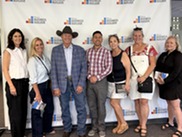 Councilmember , Mayor, and several other women standing in front of sign for Mesa business Builders