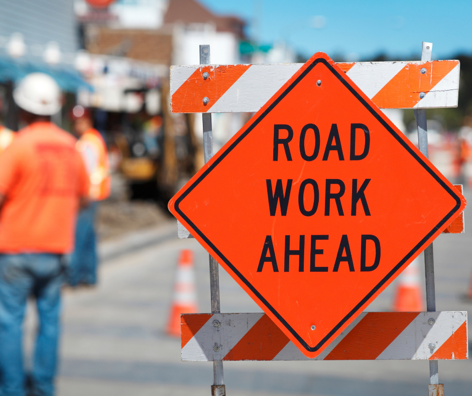 A picture of a road work sign and construction crews
