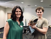Councilmember with man holding dinosaur puppet