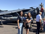 Councilmember and woman holding 2 children in front of jet