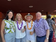 Four adults wearing Hawaiian shirts and smiling