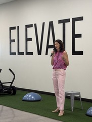 Councilmember speaking with microphone in front of Elevate sign