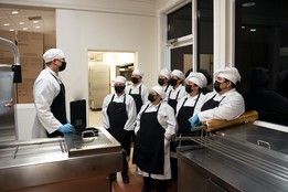 Kitchen staff standing in a clean, empty kitchen