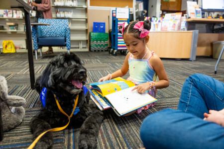 Little girl reading to a dog