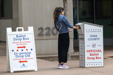 woman dropping off ballot at ballot box