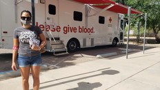 Photo of blood donor standing outside blood donation vehicle.