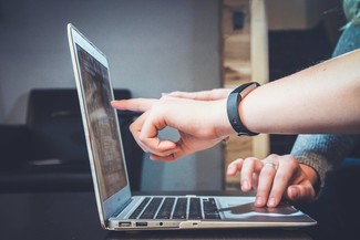 Image of two hands pointing at a laptop screen