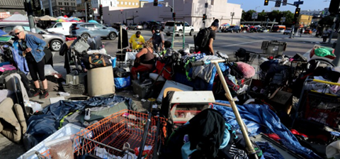 L.A. street and sidewalk filled with homeless walking among piles of garbage