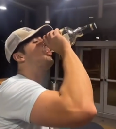 Picture shows a guy drinking alcohol from the bottom of the bottle