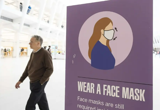 Picture shows a man without mask walk next to the wear a face mask sign