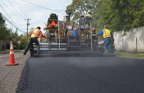 Picture of several workers put layer of asphalt in the road 