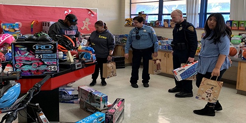Uniformed TPD members and community members stand in a school room surrounded by toys.