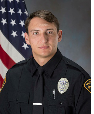 TPD department photo of Officer Chase Bryan in uniform in front of a flag.