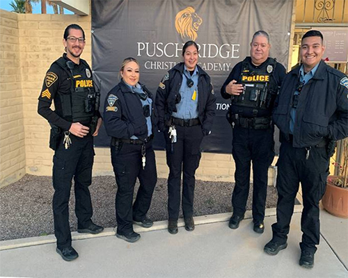 TPD Operations Division South members, in uniform, stand outside Pusch Ridge Christian Academy, in front of a school banner.