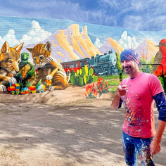 Picture shows a man in the pink shirt stands in front of the murals