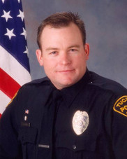 TPD Officer Jamie Voss in uniform in front of a U.S. flag