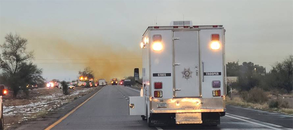 Back of Arizona State Trooper vehicle on I-10 looking toward orange cloud of hazmat incident at dusk