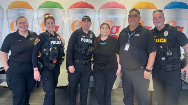 TPD ODM officers in uniform stand in front of a tasty mural display of Eegee's flavors
