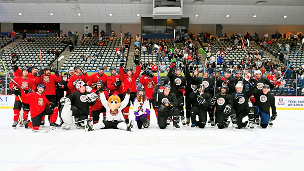 Tucson Police and Tucson Fire hockey teams lined up for a group portrait on the ice with Dusty, the Tucson Roadrunners' mascot