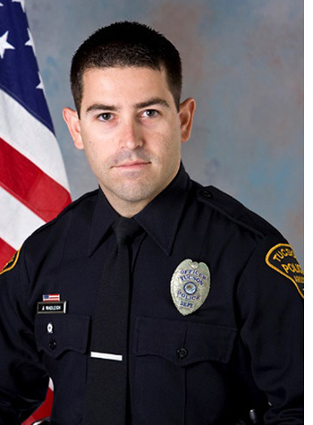 TPD Officer Wadleigh, in uniform, in front of an American flag