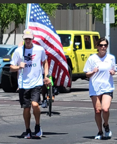 Picture of Steve Kozachik running while holding the US Flag along side of Joanna, sister of Deborah Martinez-Garibay