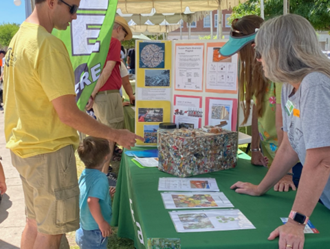 Tucson Verde Rotary booth table with people looking at the block and pictures