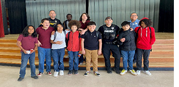 Students stand with TPD ODM officers in uniform in their school auditorium